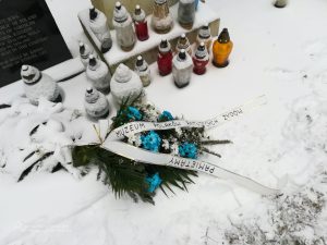 Kwiaty i znicze przed pomnikiem na cmentarzu. Zimowa aura.