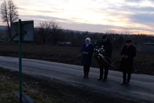 Trzyosobowa delegacja przed tablicą na tzw. Okopie