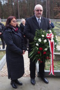 Delegacja MPRŻ z wiązanką biało-czerwonych kwiatów. W tle cmentarz wojenny w Jagielle-Niechciałkach.