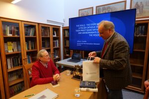 Dyrektor MPRŻ wręcza Jeffreyowi Cymblerowi upominek. W tle biblioteka