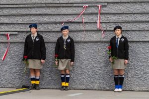 Trzy harcerki na tle Ściany Pamięci Muzeum Ulmów.