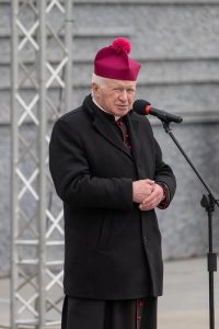 Prelegent przemawia przed Ścianą Pamięci Muzeum Ulmów.