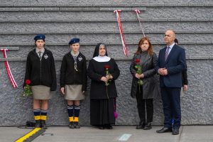 Grupa ludzi na tle Ściany Pamięci Muzeum Ulmów.