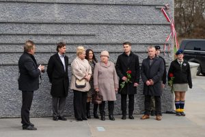 Grupa ludzi na tle Ściany Pamięci Muzeum Ulmów.