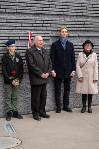 Grupa ludzi na tle Ściany Pamięci Muzeum Ulmów.