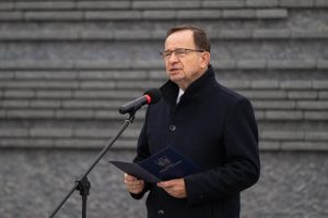 Prelegent przemawia przed Ścianą Pamięci Muzeum Ulmów.