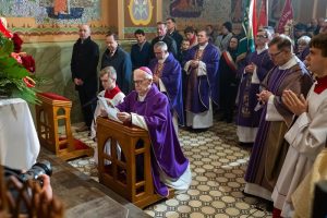 Grupa księży. Na pierwszym planie ksiądz na klęczniku.