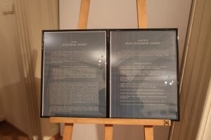 Dwie plansze z opisem Ikony Błogosławionej Rodziny Ulmów i notką biograficzną autora na sztalugach.