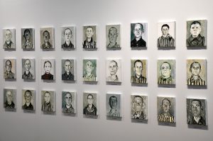 Fragment ekspozycji. Na ścianach widzą małe portrety więźniów KL Auschwitz.