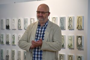 Mężczyzna bijący brawo. W tle obrazy.