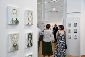 Publiczność zgromadzona na wernisażu wystawy portretów olejnych.