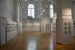 Fragment sali wystawowej. Na ścianach widzą małe portrety więźniów KL Auschwitz.