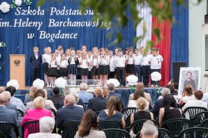 Grupa dzieci występuje na plenerowej scenie. Przed nią widzowie.