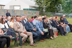 Grupa osób podczas plenerowej uroczystości.