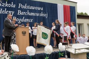 Młodzież ze sztandarem na plenerowej scenie.