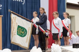 Młodzież ze sztandarem na plenerowej scenie.