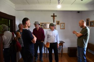 Grupa osób zwiedza starą chałupę.