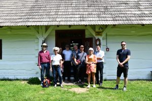 Grupa osób przed starą chałupą.