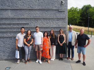 Grupa osób pozuje na tle Ściany Pamięci MPRŻ