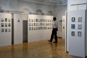 Mężczyzna zwiedza wystawę portretów olejnych.