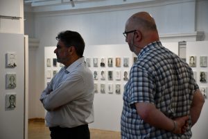 Mężczyzna zwiedza wystawę portretów olejnych.