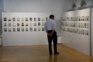 Mężczyzna zwiedza wystawę portretów olejnych.