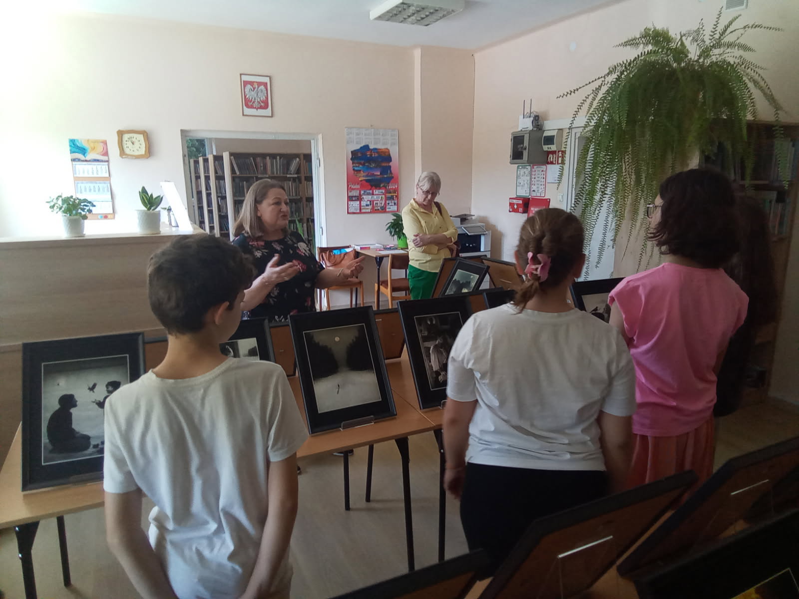 Spotkanie wokół wystawy "Anawim". Przed obrazami stoją dzieci, opiekun i przewodnik muzealny.