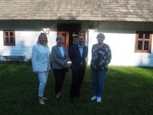 Tibor Gerencsér, Konsul Generalny Węgier w Krakowie wraz z małżonką i towarzyszącymi im osobami pozują na tle Chałupy Szylarów w markowskim skansenie.