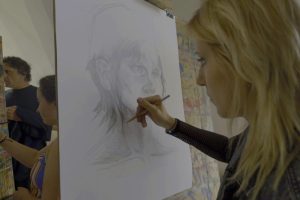 Uczennica szkoły plastycznej rysuje portret.