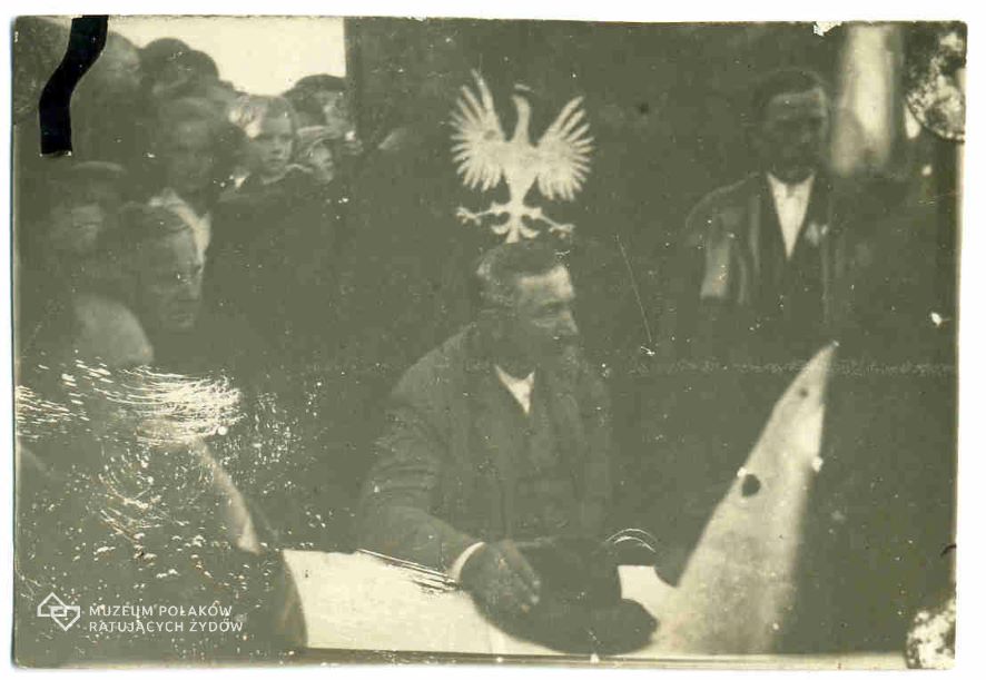 Wincenty Witos na tle kurtyny z orłem.